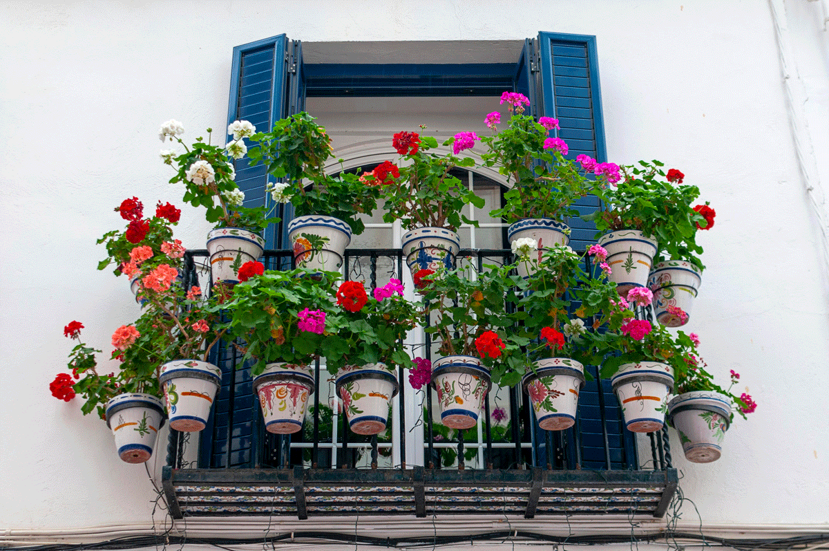 Ambiance cosy sur un balcon DIY avec guirlande solaire, coussins, pots peints et matières naturelles